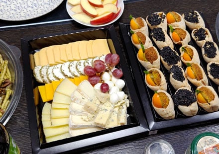 Catering trays with cheeses, grapes, and savory pastries